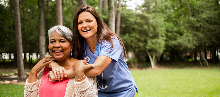 A nurse and a senior woman smiling